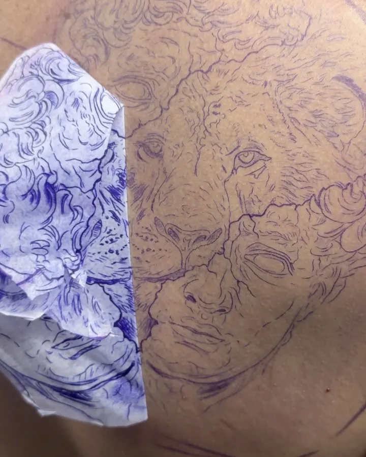 Violet stencil of a lion and a statue mapped across a client's back